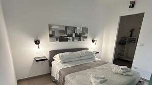 A modern bedroom with a bed, nightstands, a wall art piece, and a closet.