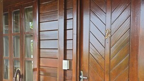 A wooden door with a number 2, a glass door with a chair, and a tiled floor. - Pousada Capim Açu (Fernando de Noronha)