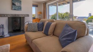 Una sala de estar moderna con un sofá color beige, una chimenea y un amplio ventanal con vistas a la ciudad.