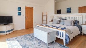 Un dormitorio con cama, mesita de noche, lámpara, televisión y una escalera de madera.