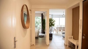 A modern interior with a hallway leading to a dining area, featuring a potted plant, a wooden bench, and a large mirror. - Comfortable apartment in the heart of Antibes (Antibes)