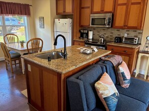 A kitchen with wooden cabinets, a granite countertop, a sink, a refrigerator, a microwave, a stove, and a toaster.
