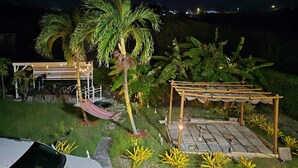 A nighttime outdoor setting with a hammock, a wooden pergola, and a car parked nearby. - Genesis King Suite Apt 4 located in peaceful valley AC, Wi-Fi, King Bed (Cassada Gardens)