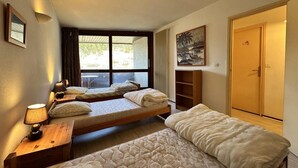 Une chambre avec deux lits, une table de chevet avec une lampe, une armoire et un tableau au mur.