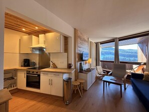 A compact living space with a kitchenette, a dining area, and a seating area with a view.