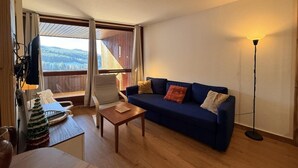 Un salon chaleureux avec un canapé bleu, une table basse en bois et un petit sapin de Noël.