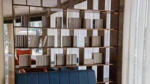 A modern interior with a blue sofa, a bookshelf with books, and a view through a window. - Shishi Live DNG Hotel (Shishi)