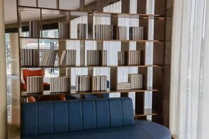A room with a blue sofa, a bookshelf, and a window. - Shishi Live DNG Hotel (Shishi)