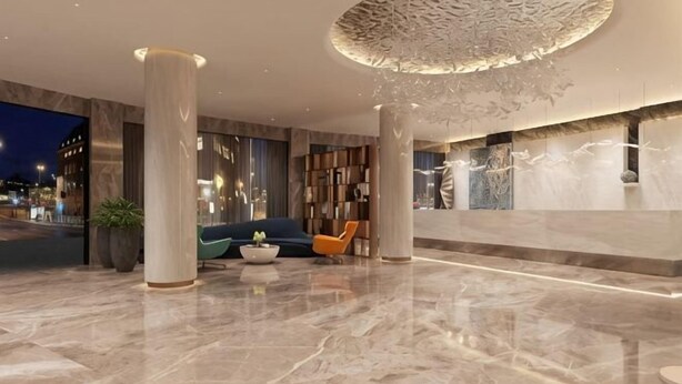 A modern lobby with marble flooring, a central seating area with a sofa and chairs, a large decorative ceiling feature, and a reception desk. - Shishi Live DNG Hotel (Shishi)