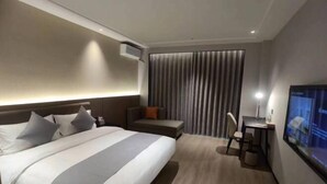 A hotel room with a bed, a desk, a chair, a TV, and a window with curtains. - Shishi Live DNG Hotel (Shishi)