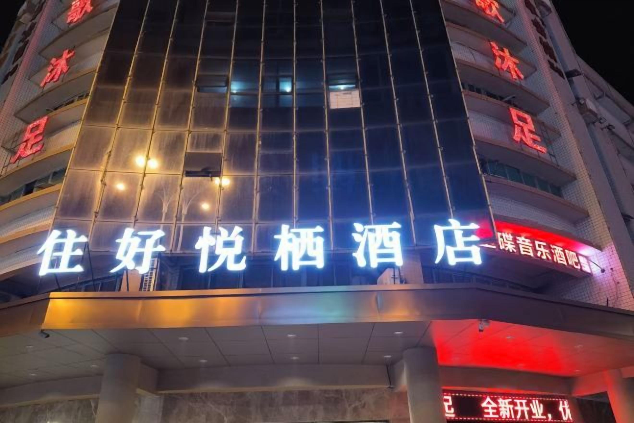 A hotel with illuminated signage in a foreign language, multiple floors, and a modern architectural design.