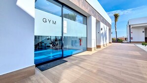 Ett modernt gym med glasväggar, en brandsläckare och en klar himmel.