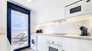 Ett modernt kök med tvättmaskin, ugn, mikrovågsugn och kaffebryggare.