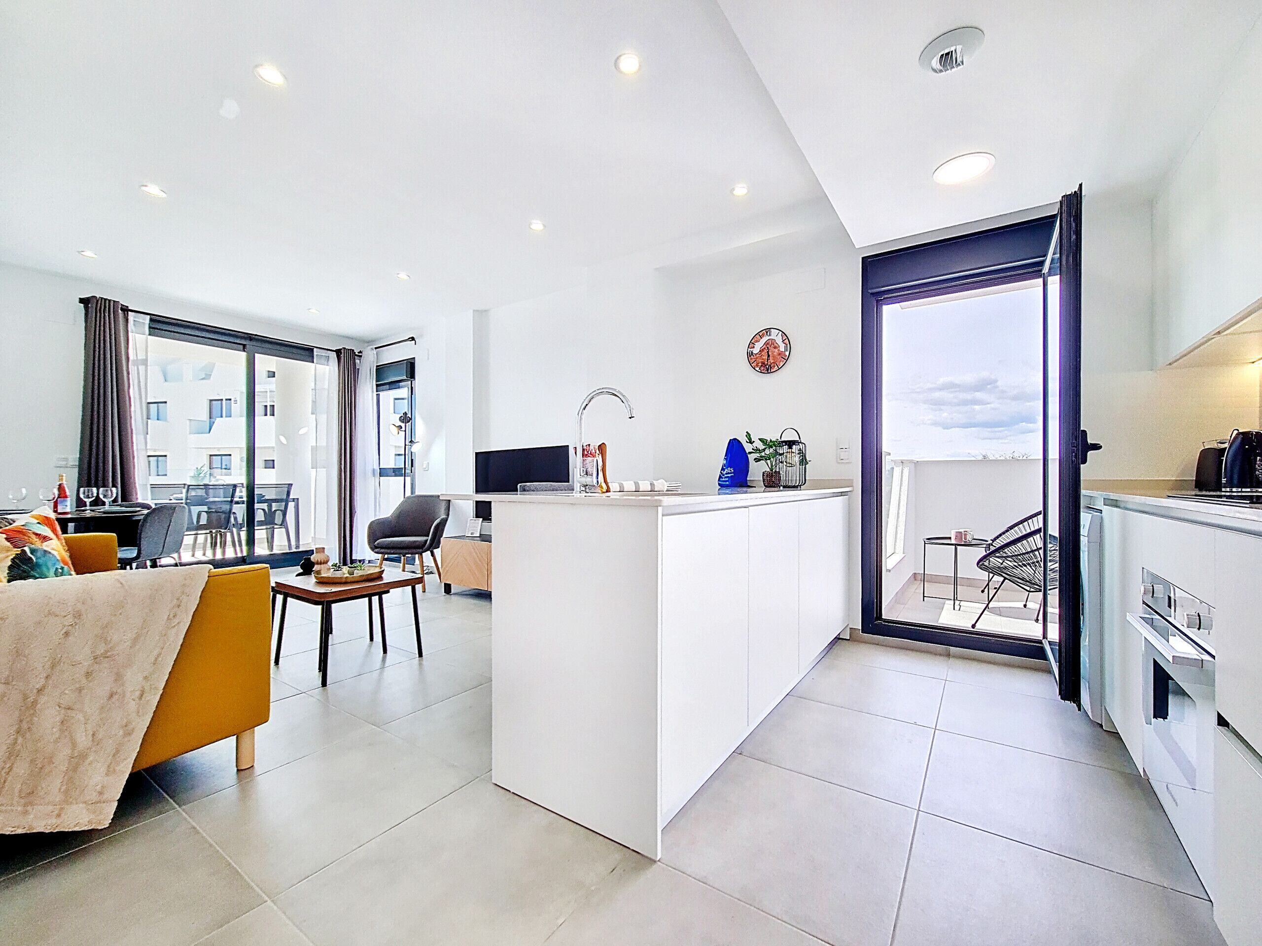 A modern apartment with a living area, a kitchen, and a balcony.