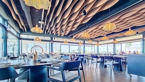 En modern restaurang med en unik takdesign, stora fönster och stilrena möbler.