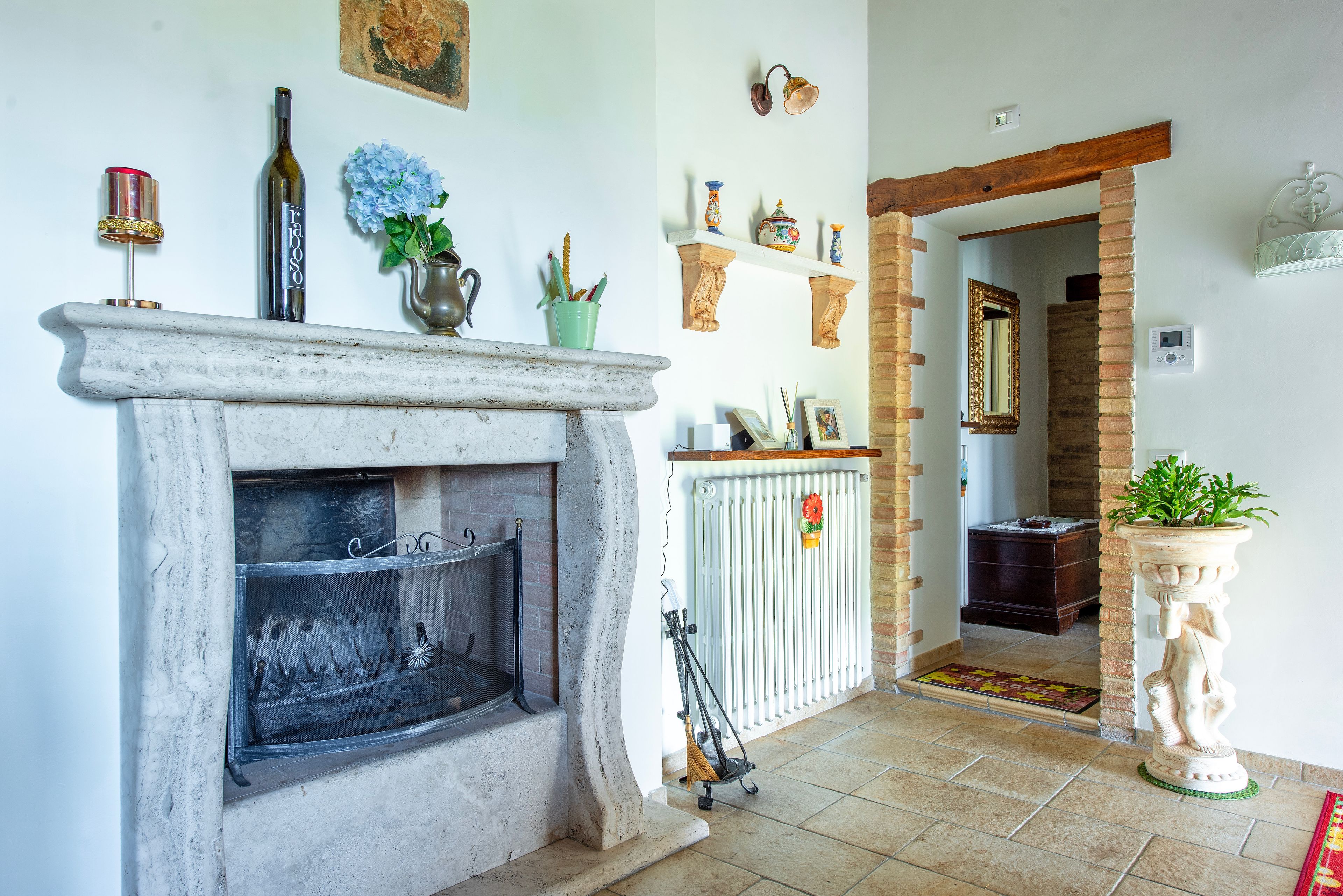 A fireplace with a screen, a wooden mantel, and various decorative items including a bottle, a vase, and a small plant.
