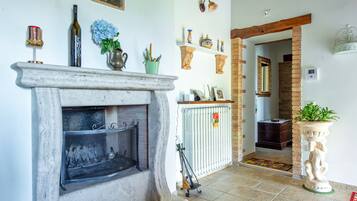A fireplace with a screen, a wooden mantel, and various decorative items including a bottle, a vase, and a small plant.