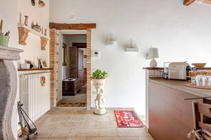 Una cocina con chimenea de piedra, techo con vigas de madera y suelo de baldosas.