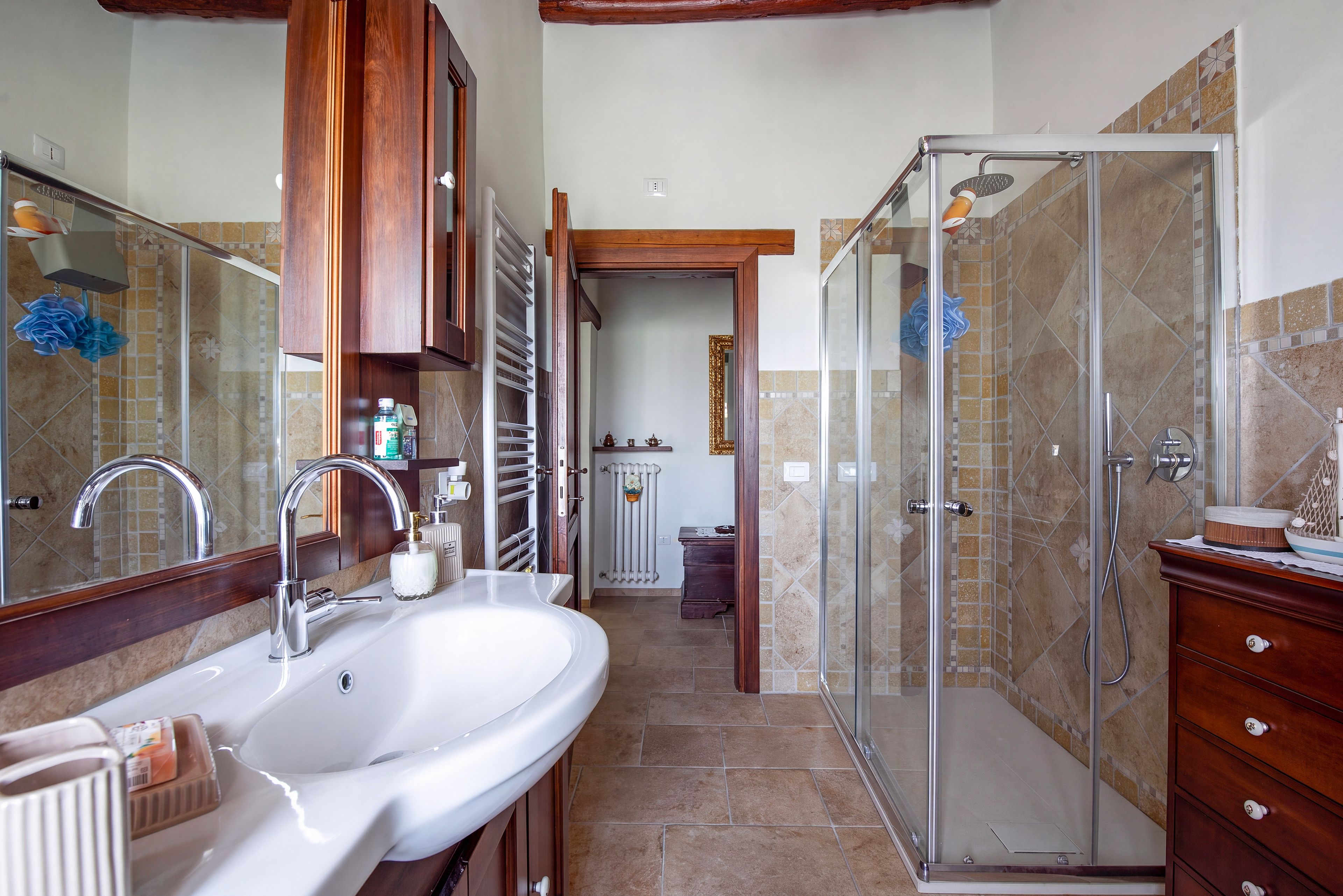 A bathroom with a double sink, a shower enclosure, and a wooden vanity.