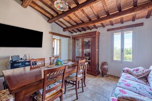 A dining area with a wooden table, chairs, a cabinet, and a television mounted on the wall. - Athena Residence: Vacation Rental (Umbria)
