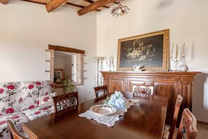 A dining area with a wooden table, floral sofa, and a painting above the fireplace. - Athena vacation home (Umbria)