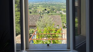 A window with a view of a rural landscape, including fields and distant hills.