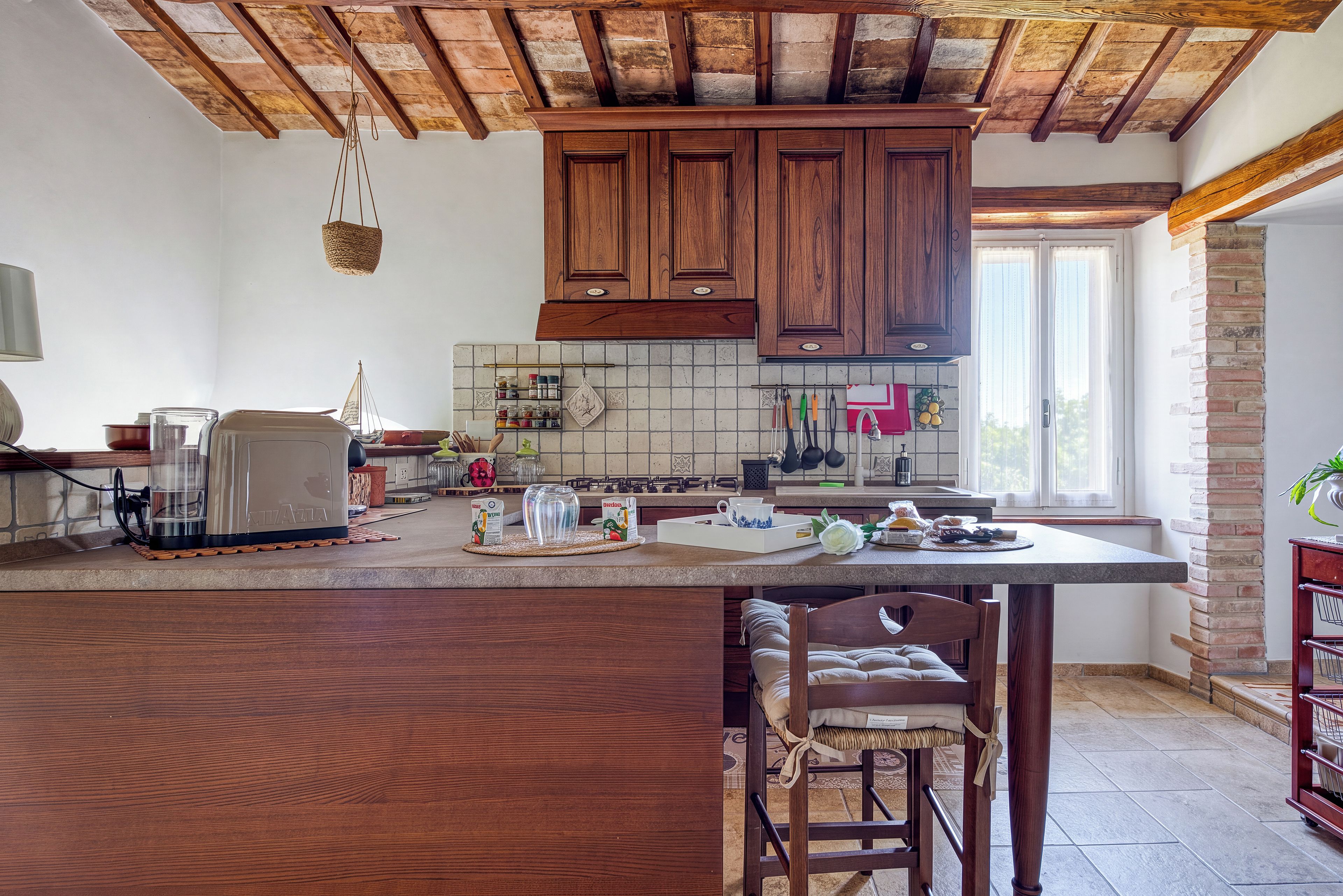 A kitchen with wooden cabinets, a large island, and a hanging light fixture.