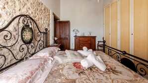 A bedroom with a bed, a wooden wardrobe, a nightstand, and a chandelier.