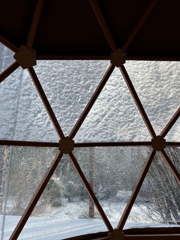 A window with a diamond pattern, through which a snowy landscape is visible.