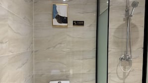Un baño con paredes de mármol, ducha e inodoro.