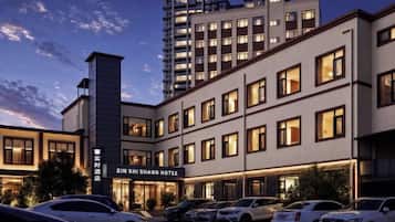 A hotel with a modern facade, multiple floors, and a parking lot with several cars.