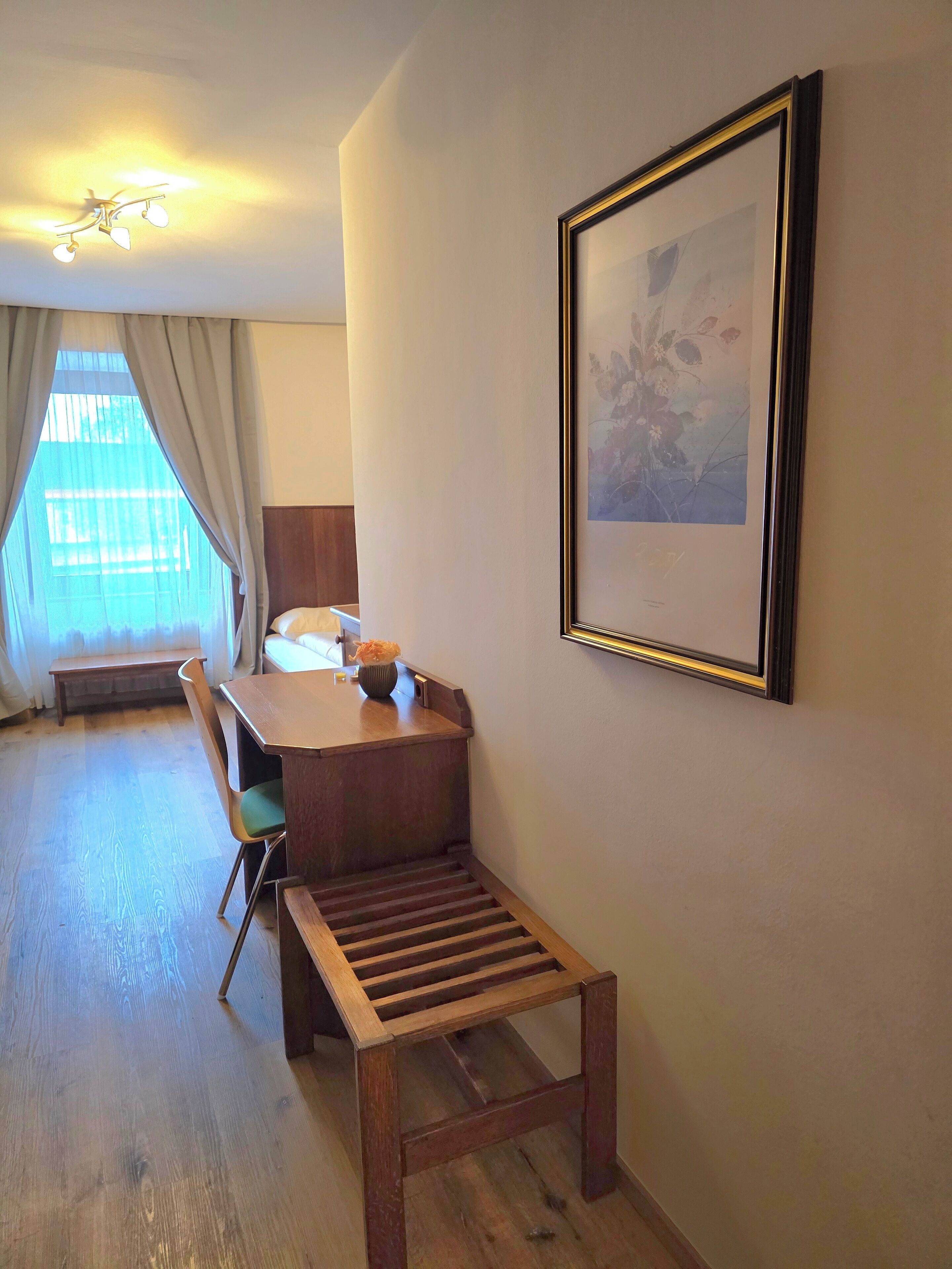 A room with a wooden dining table, a bench, a framed picture on the wall, and a ceiling fan.