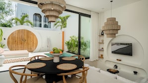 Un comedor moderno con una mesa redonda, individuales tejidos y sillas de madera.