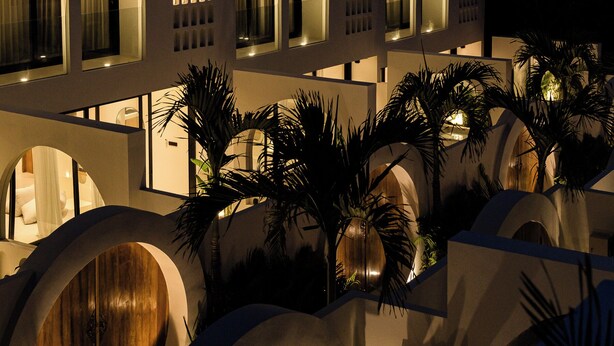 Un edificio moderno con varias ventanas arqueadas y un patio con palmeras.