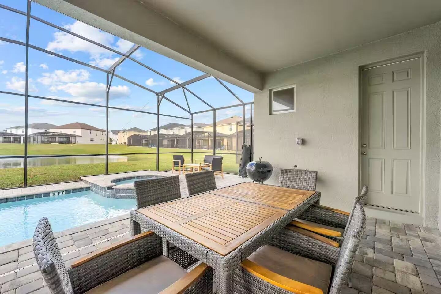 A covered patio with a pool, outdoor seating, and a view of the neighborhood.