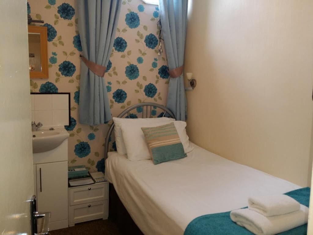 Una camera da letto con un letto, un comodino, un lavandino e uno specchio.