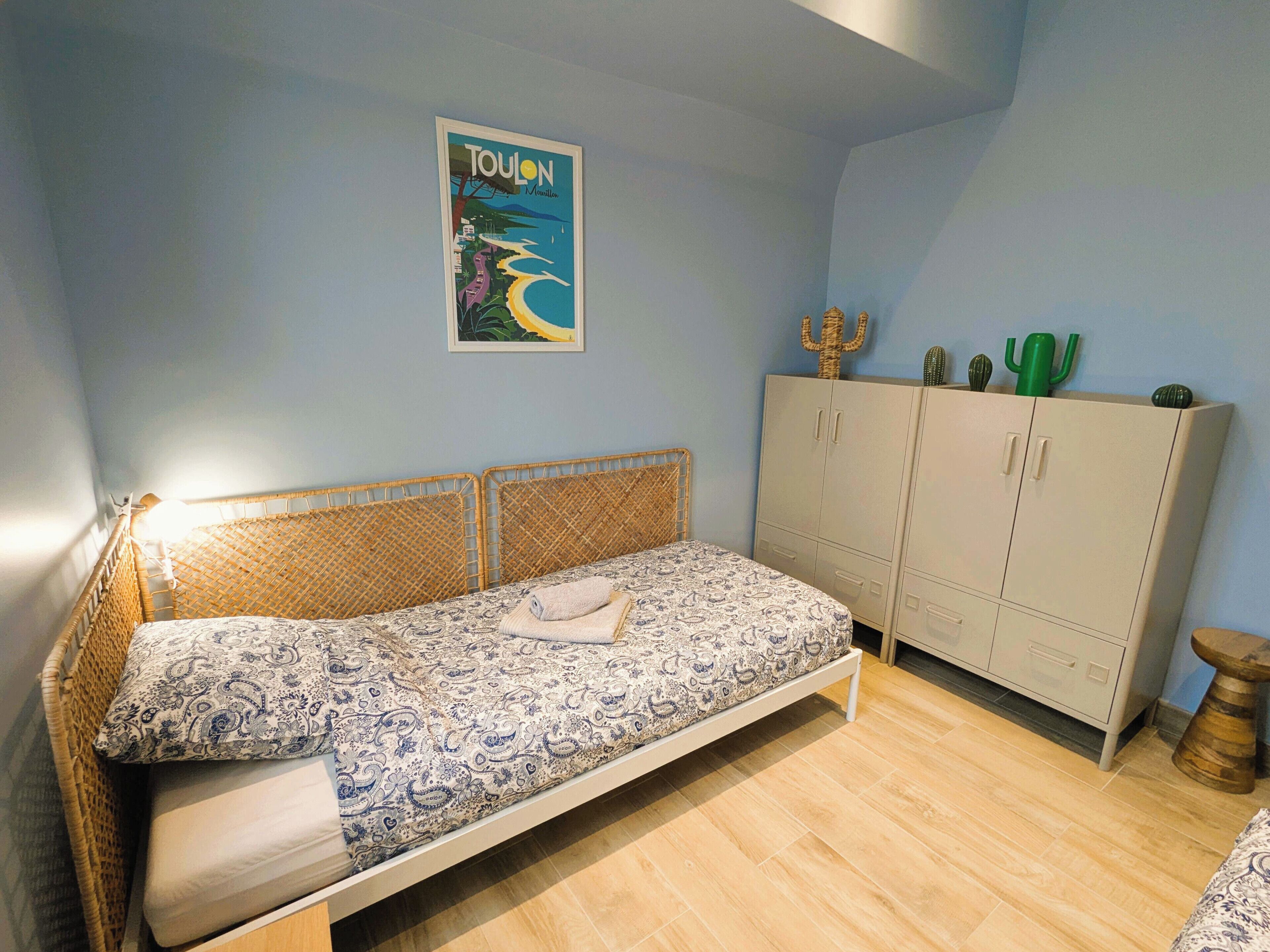 A bedroom with a bed, a wardrobe, and a poster on the wall.