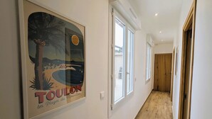 A hallway with a framed poster, large windows, and wooden flooring. - Penthouse with large terrace, near beaches (Toulon)