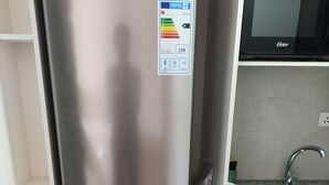 Eine kompakte Küche mit einem Edelstahl-Kühlschrank, einer Waschmaschine und einer Mikrowelle.