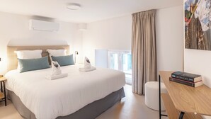 A modern hotel room with a large bed, a bedside table with books, a window with curtains, and a painting on the wall. - Cosy T2 in Cannes (Cannes)