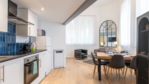 A modern kitchen with a microwave, oven, and a dining area with a table and chairs. - Cosy T2 in Cannes (Cannes)