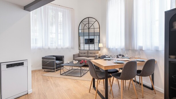A modern living room with a dining area, featuring a sofa, a coffee table, and a dining table set for four. - Cosy T2 in Cannes (Cannes)