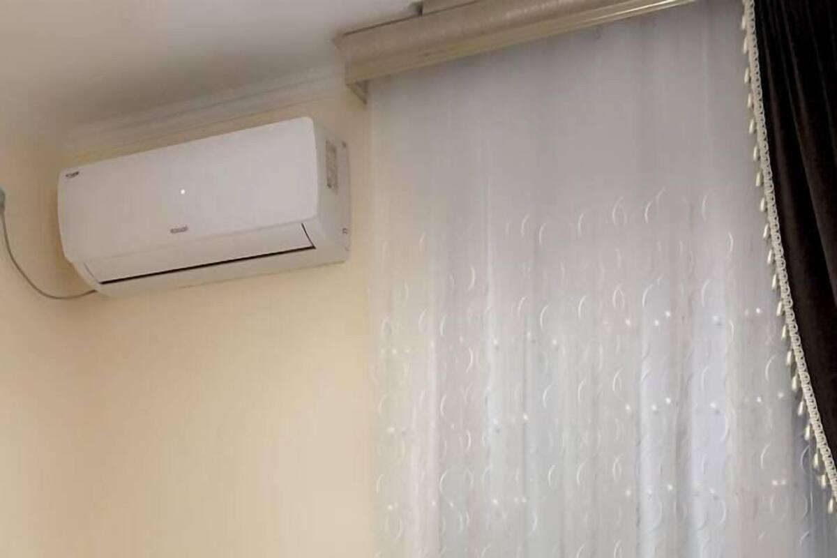 A hotel room with two beds, a nightstand with toiletries, and an air conditioning unit on the wall.