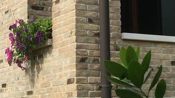 Un edificio de ladrillo con una ventana y una maceta con flores moradas.