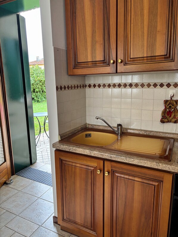 Una cocina con armarios de madera, un lavamanos y un salpicadero de azulejos.