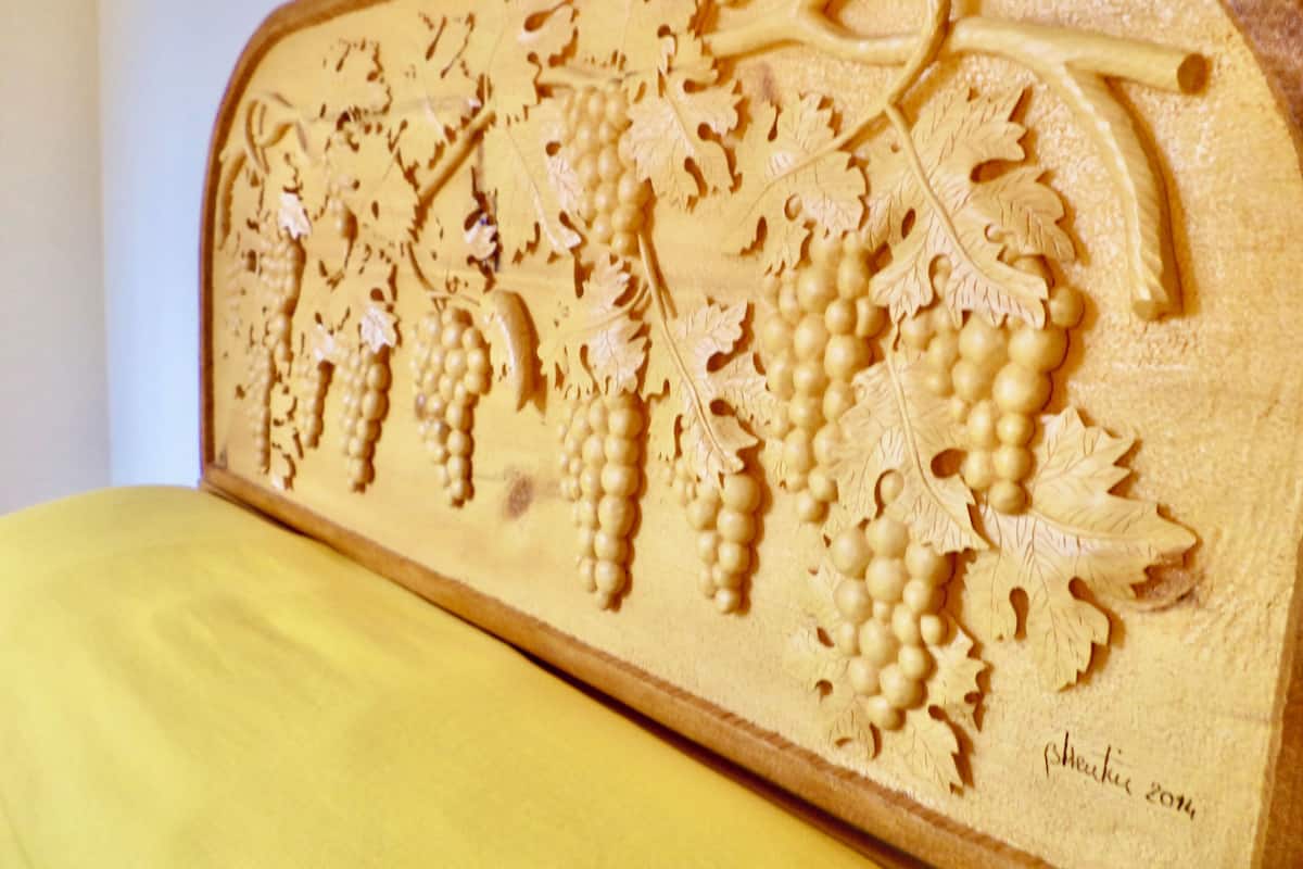 A wooden carving of grapes and leaves on a table.