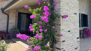 A brick building with a covered porch and flowering plants. - B&B Alla Suite (Pieve di Soligo)