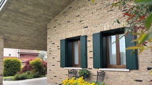 A brick building with two windows and a covered patio area. - B&B Alla Suite (Pieve di Soligo)