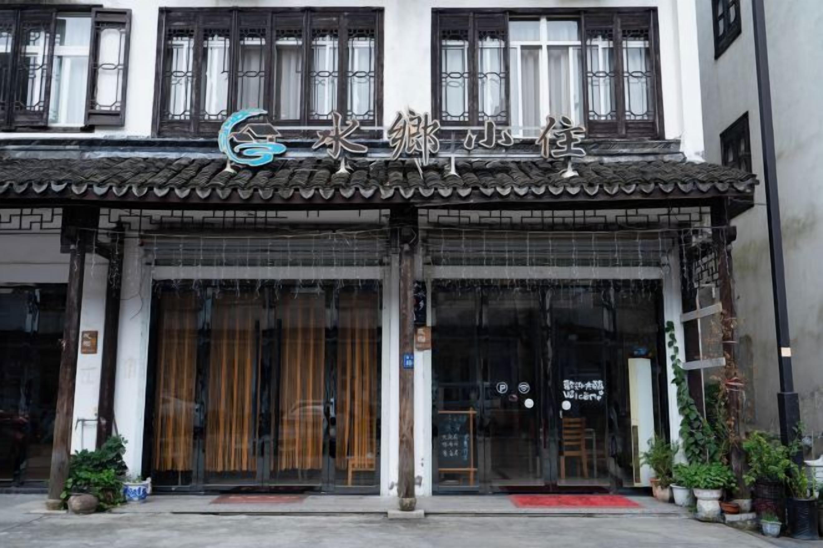 A traditional building with a tiled roof, large glass doors, and a sign with Chinese characters.