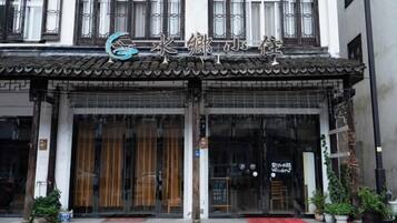 A traditional building with a tiled roof, large glass doors, and a sign with Chinese characters.